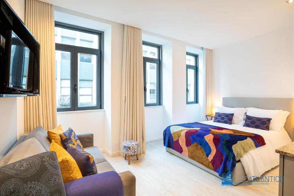 een slaapkamer met een bed, een bank en ramen bij Porto Formosa Central Lofts in Porto