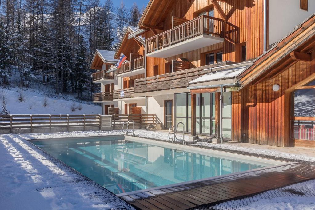 une piscine dans la neige à côté d'un bâtiment dans l'établissement Chalet Orée des pistes - Piscine et sauna, aux Orres