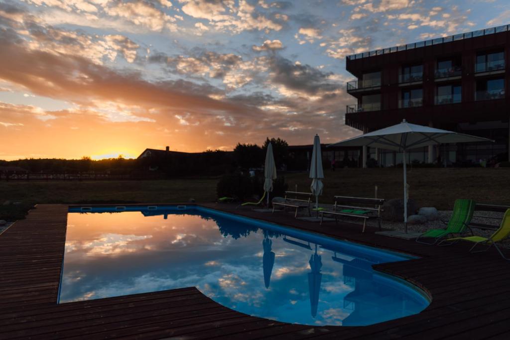 a pool in front of a building with a sunset at K-Triumf Resort in Velichovky