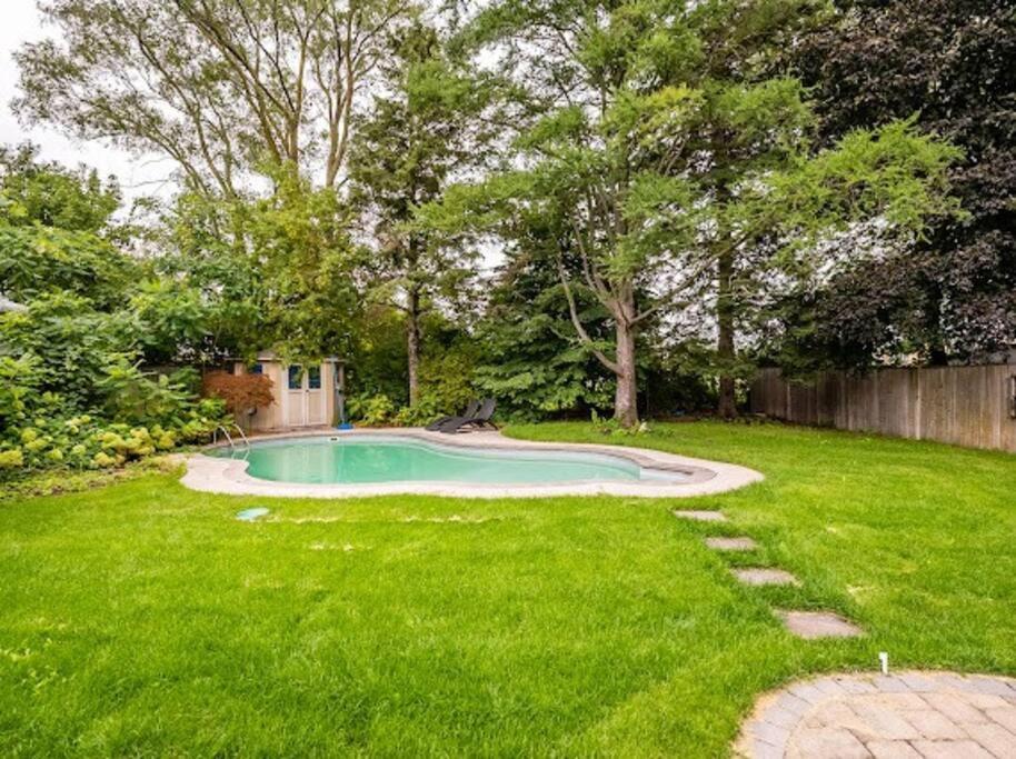 a backyard with a pool in the grass at Gorgeous 4BR House with pool in Mississauga