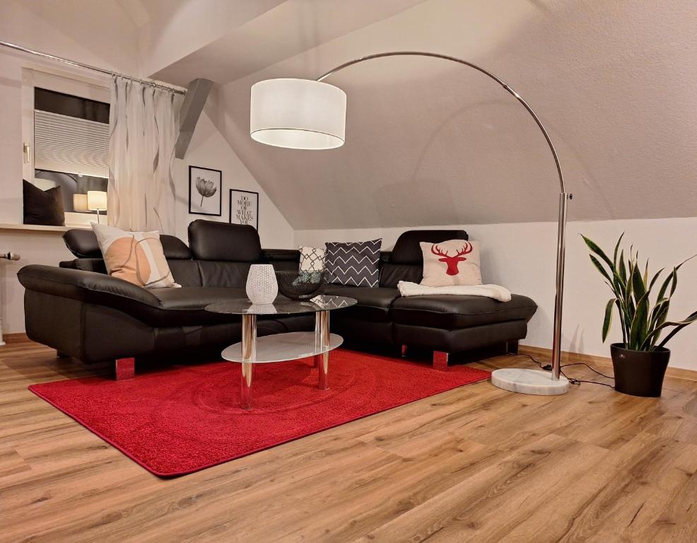een woonkamer met een zwarte bank en een rood tapijt bij Fewo im Harz für 4 Gäste mit optionalem Brötchenservice in Zorge