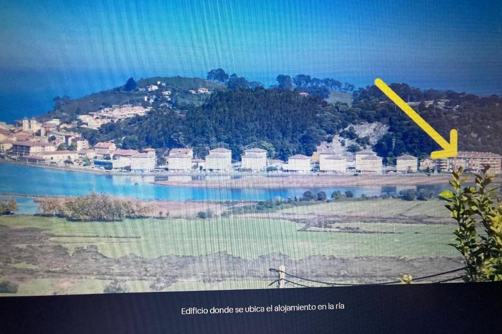 Uma flecha amarela está a apontar para uma cidade numa colina. em Rincon en el Rio Sella em Ribadesella