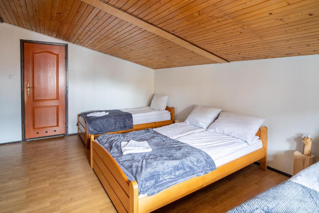 two beds in a room with a wooden ceiling at VacationClub - Ski Lodge Szczyrk Pokój 4 in Szczyrk
