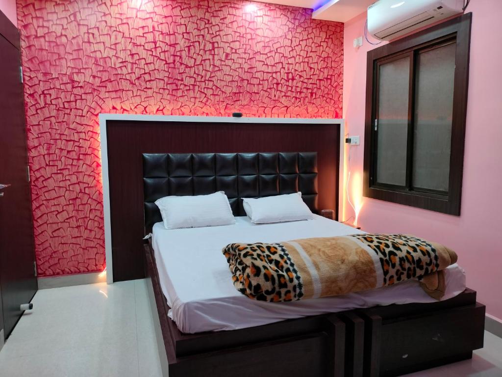 - une chambre avec un lit et un mur rose dans l'établissement HOTEL GANESH PALACE, à Aurangābād