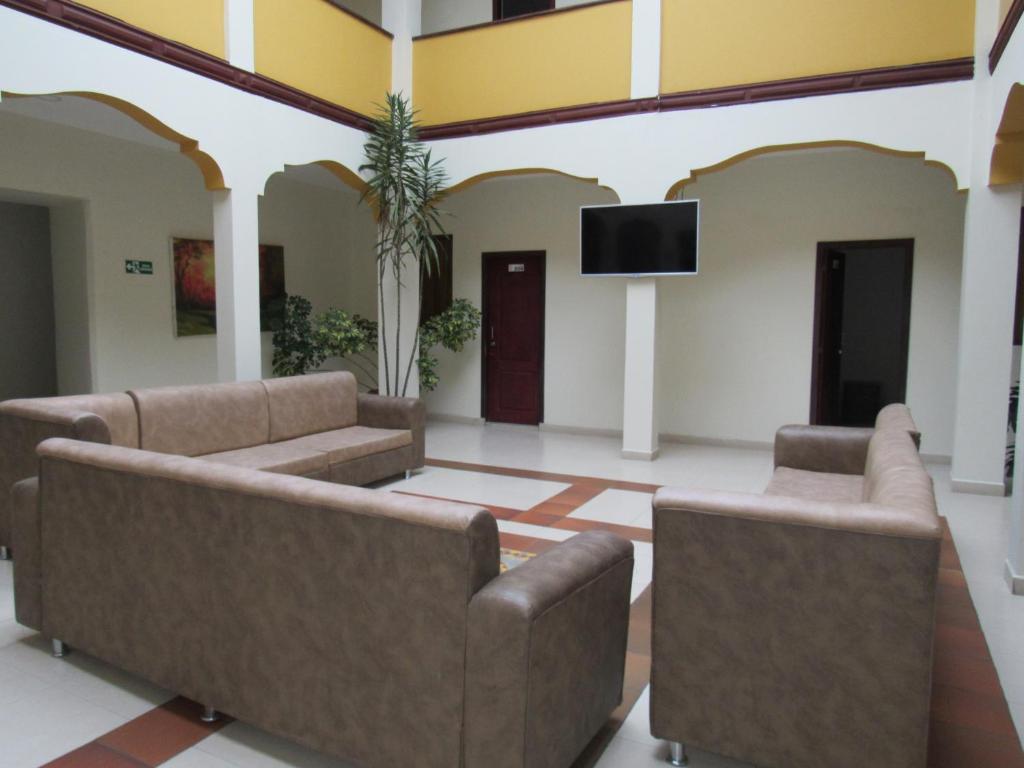 ein Wohnzimmer mit 2 Sofas und einem Flachbild-TV in der Unterkunft HOTEL COLONIAL in Ipiales