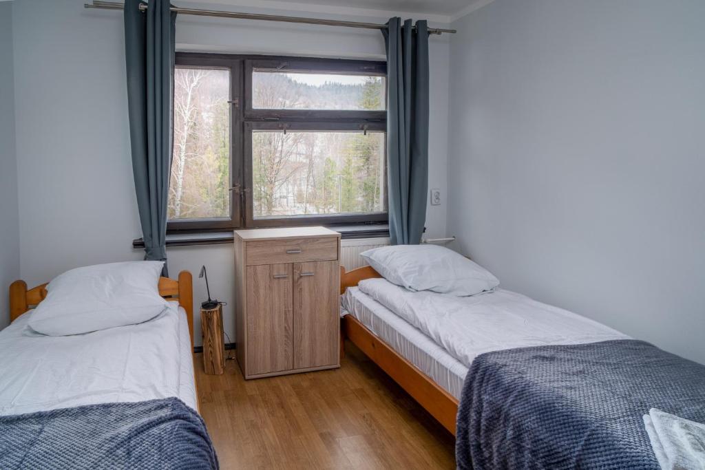two twin beds in a room with a window at VacationClub - Ski Lodge Szczyrk Pokój 6 in Szczyrk