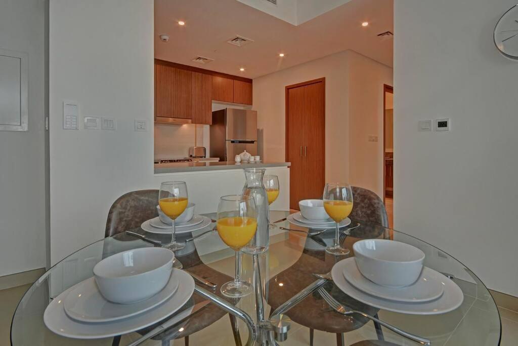 a glass dining room table with glasses of orange juice at Beachwalk Luxury 2BR with Infinity Pool and Views in Dubai