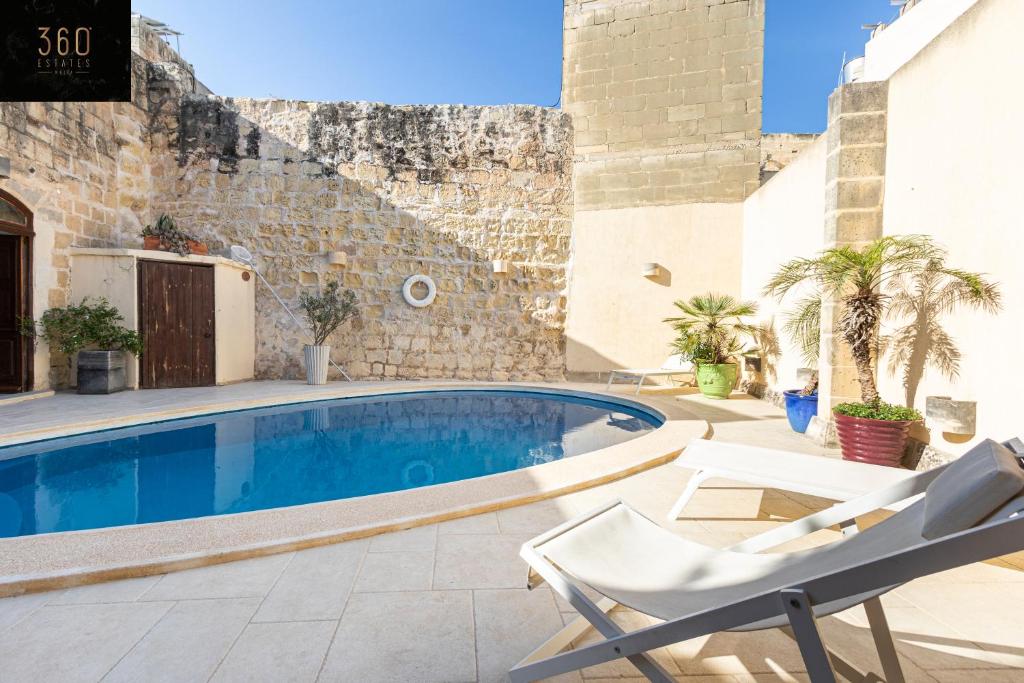 a swimming pool with a chair next to a building at A stunning, townhouse with magnificent pool area by 360 Estates in Żebbuġ