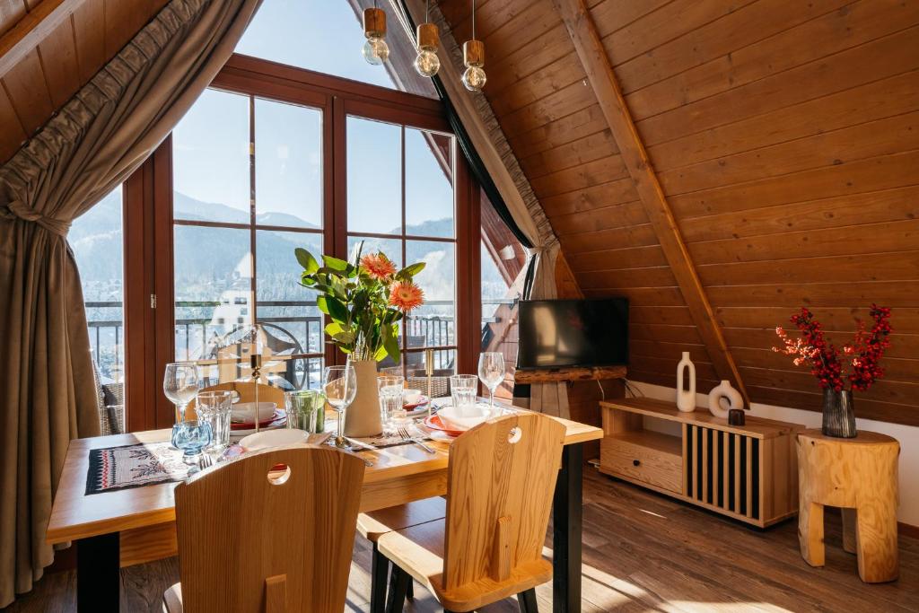 - une salle à manger avec une table, des chaises et des fenêtres dans l'établissement Highlander by LoftAffair, à Kościelisko