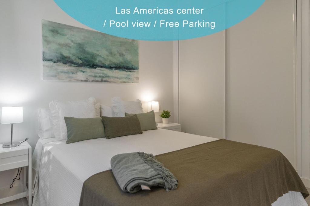 um quarto com uma grande cama branca e um cobertor em GO2TENERIFE Apart'Jara Pool view & Beach at 5 min em Playa de las Americas