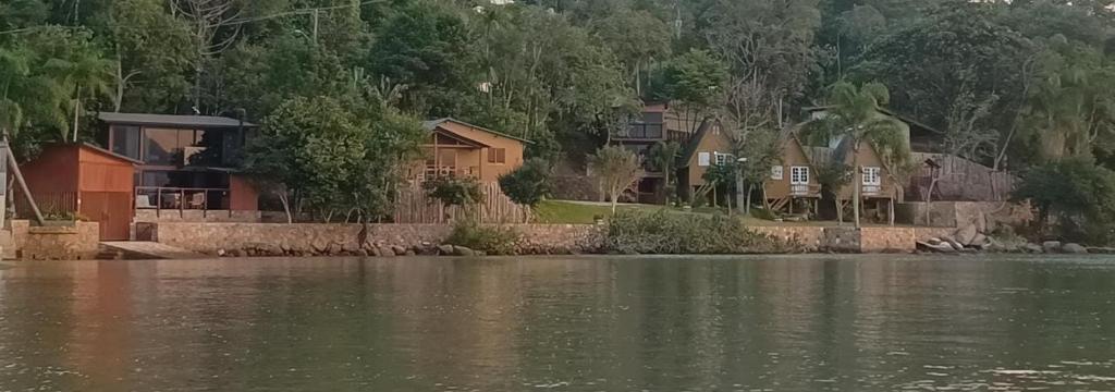 a group of houses on the shore of a lake at Grandi Pousada Sports - Sambaqui - Chalé Jurerê, Chalé da Mole e 3 Cabanas in Florianópolis