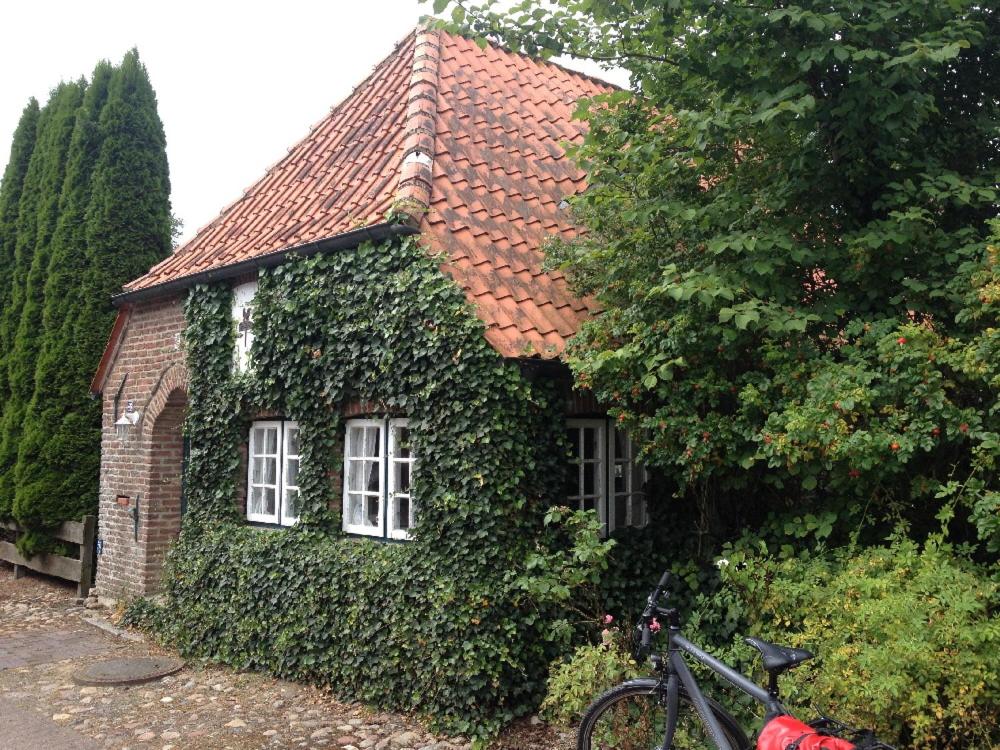 una casa cubierta de hiedra con una bicicleta estacionada al lado en Doktors Hus, en Oldenswort