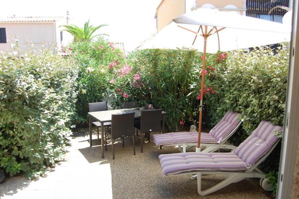 une terrasse avec 2 chaises et une table avec un parasol dans l'établissement Village naturiste - Cap sauvage - Villa les lauriers, au Cap d'Agde