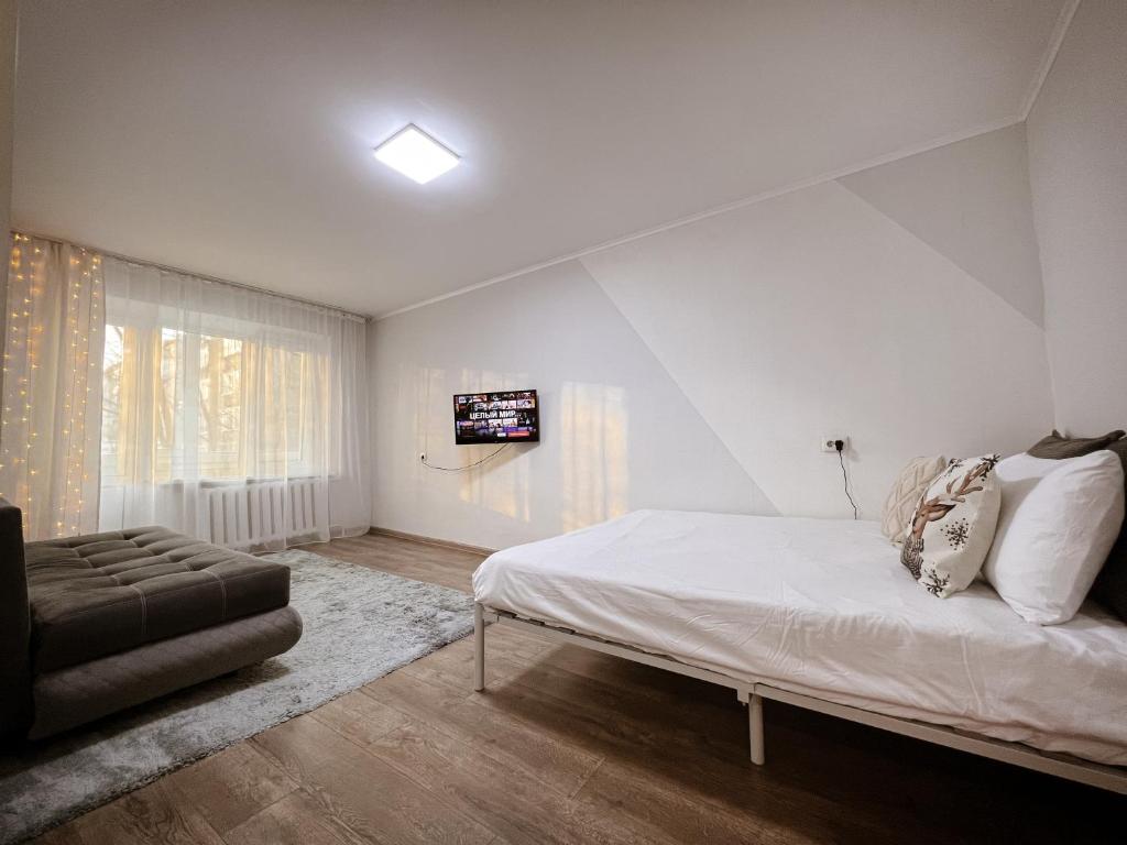 a white bedroom with a bed and a couch at Квартира в тихом районе правого берега Астаны in Astana