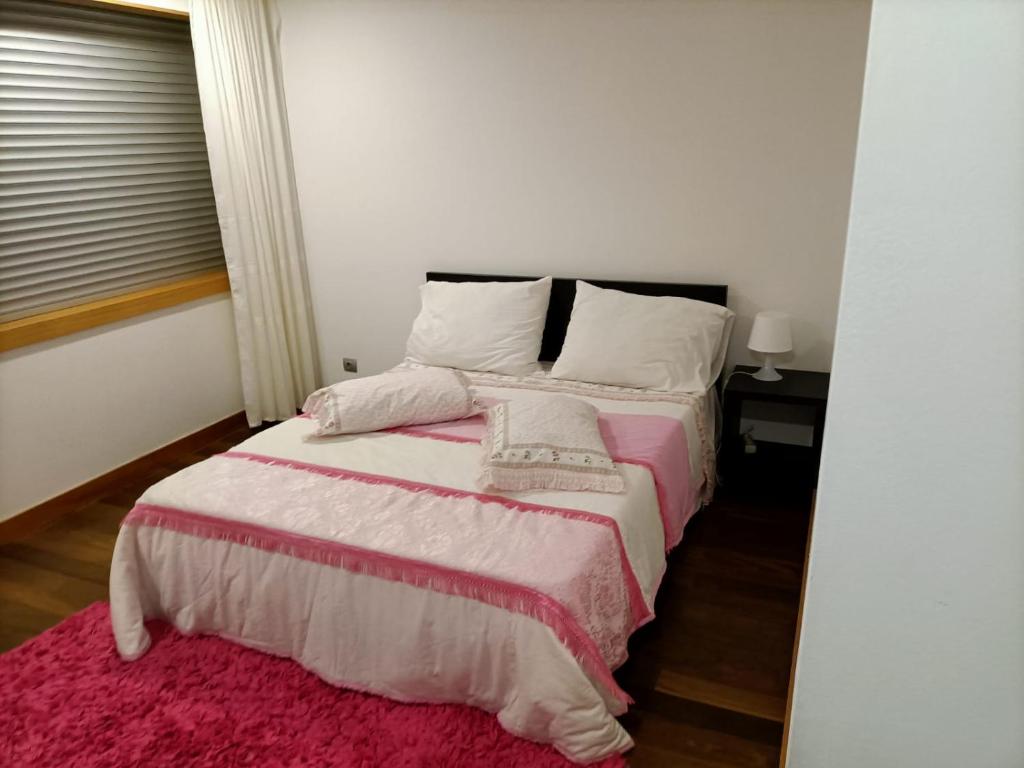 um quarto com uma cama com um cobertor rosa em O Cantinho do Arnaldo em Viana do Castelo