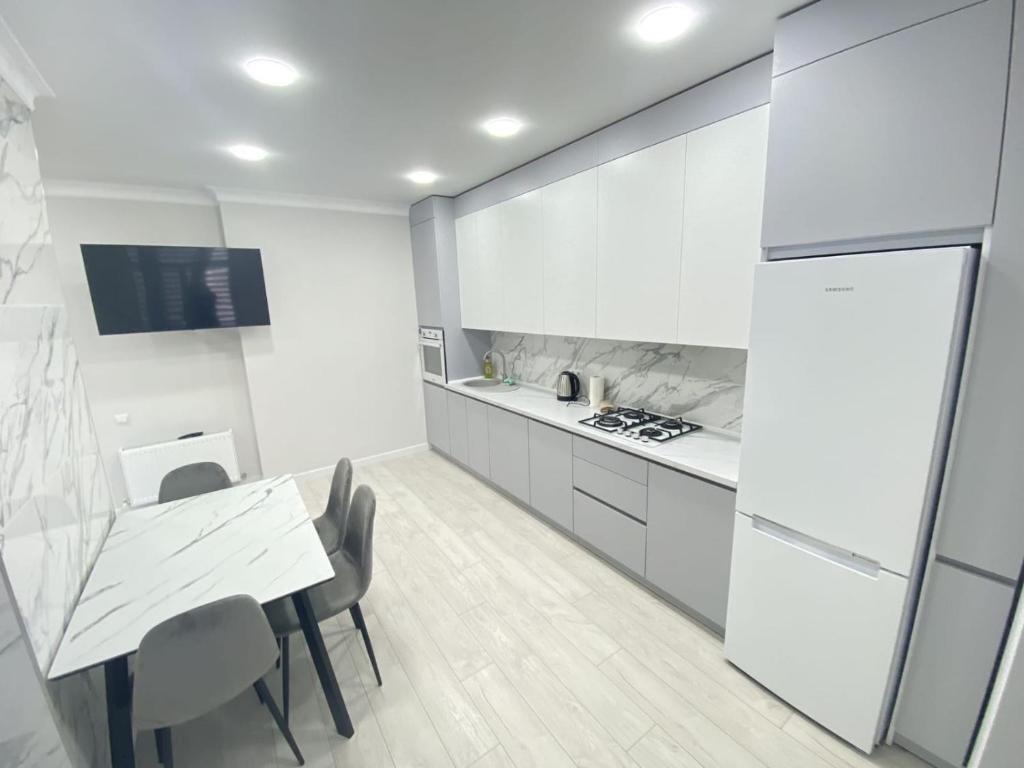 een keuken met witte kasten en een tafel en stoelen bij The Perfect and Luxury Apartment at Avrram Iancu in Chişinău