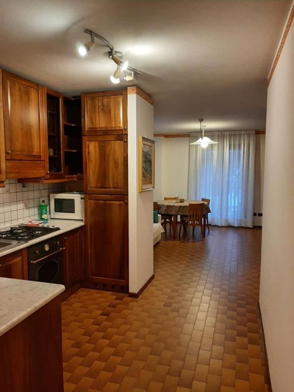a kitchen with wooden cabinets and a dining room with a table at CIVICO 43/B in Chiesa in Valmalenco