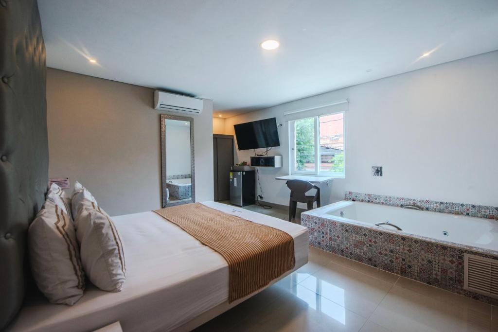 a hotel room with a bed and a bath tub at Infinity Hotel in Medellín