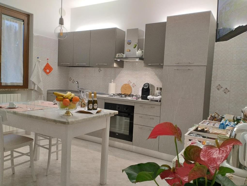 a white kitchen with a white table and a counter at A CASA IDA in Bagnoregio