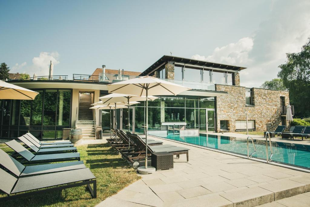a house with a swimming pool with chairs and umbrellas at Hotel Lauterbad in Freudenstadt