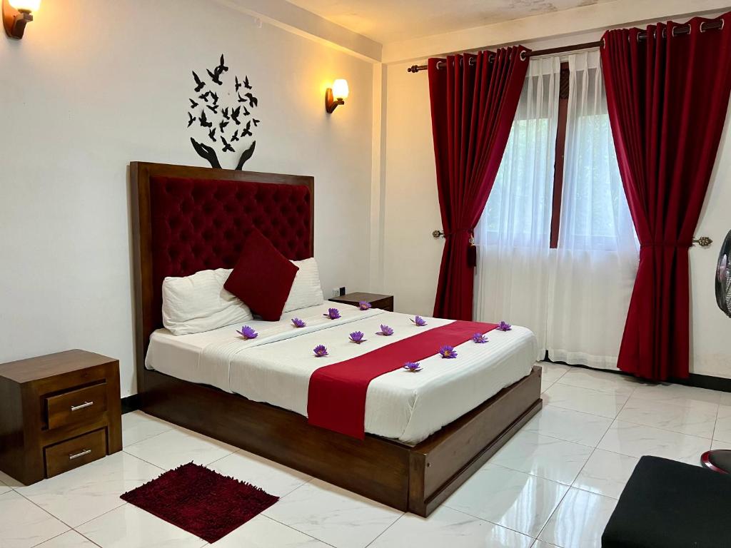 a bedroom with a large bed with red curtains at Heaven Breeze in Kandy