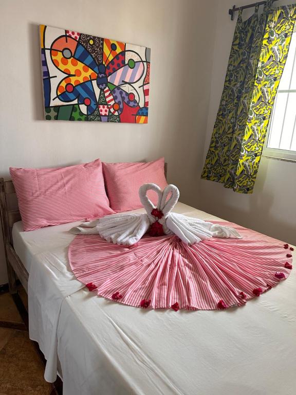 a bed with a pink and white dress on it at Pousada lagoa da Barra Taiba in Taíba