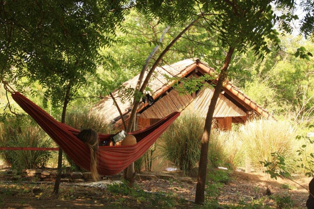 a person sleeping in a hammock in front of a hut at Camping Ojo de Agua in Nagarote