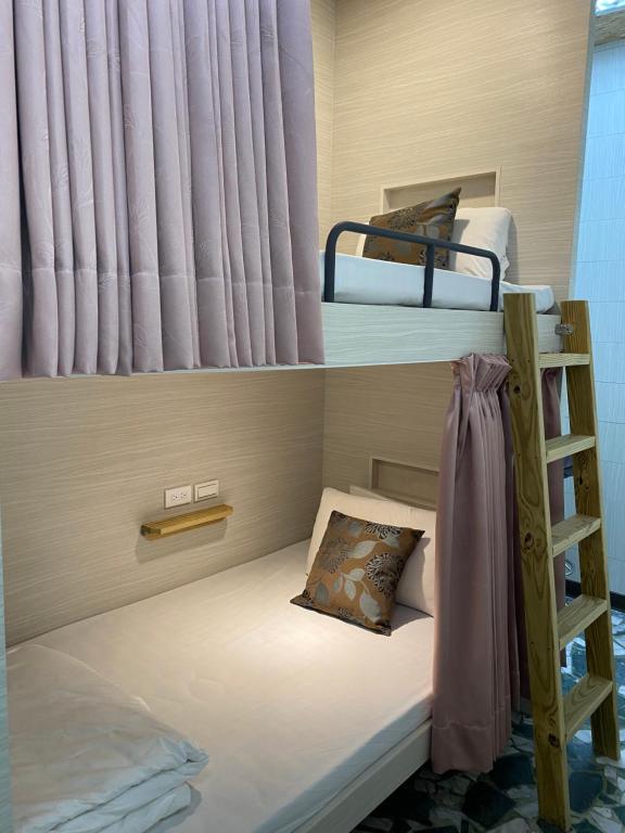 a small room with two bunk beds and a ladder at Kenting Heng-Chung Art Hostel in Hengchun