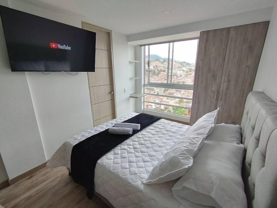 a bedroom with a bed with a television on the wall at Vista Paradisíaca, Centro Histórico de Bogotá in Bogotá