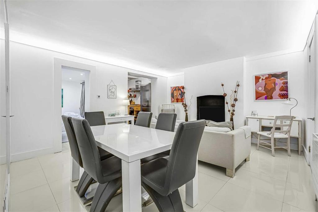 a white dining room with a white table and chairs at Earls Court Spacious Apartment in London