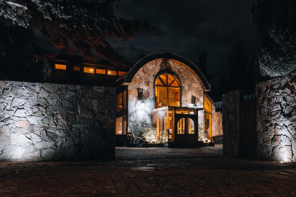 una vieja casa de piedra por la noche con luces en HOTEL NOMADES PATAGONIA, en Coyhaique