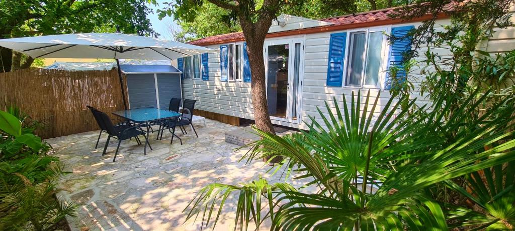 eine Terrasse mit einem Tisch, Stühlen und einem Sonnenschirm in der Unterkunft Kamp Slanik Mobile Homes in Umag