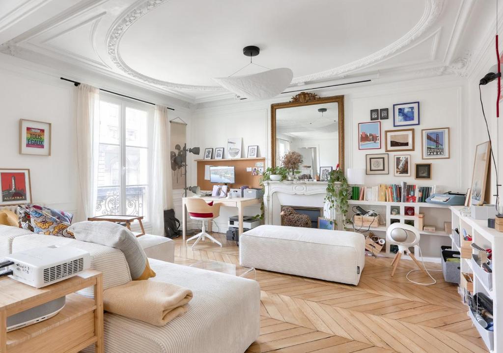 Elle comprend un salon doté d'un mobilier blanc et d'un miroir. dans l'établissement Gorgeous, bright & large 1 BR near Montmartre, à Paris