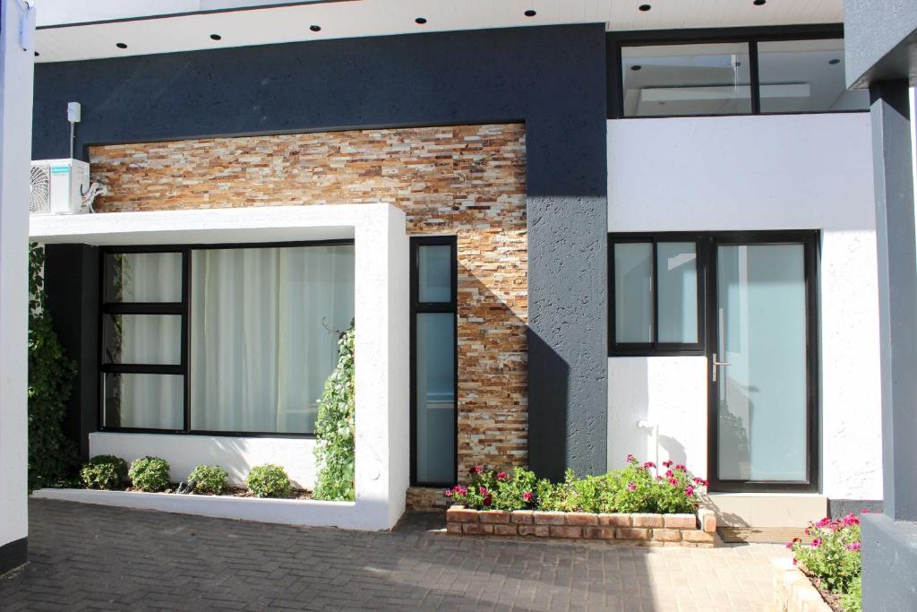 a brick house with black windows and flowers in front at Deluxe Residence - Windhoek in Windhoek