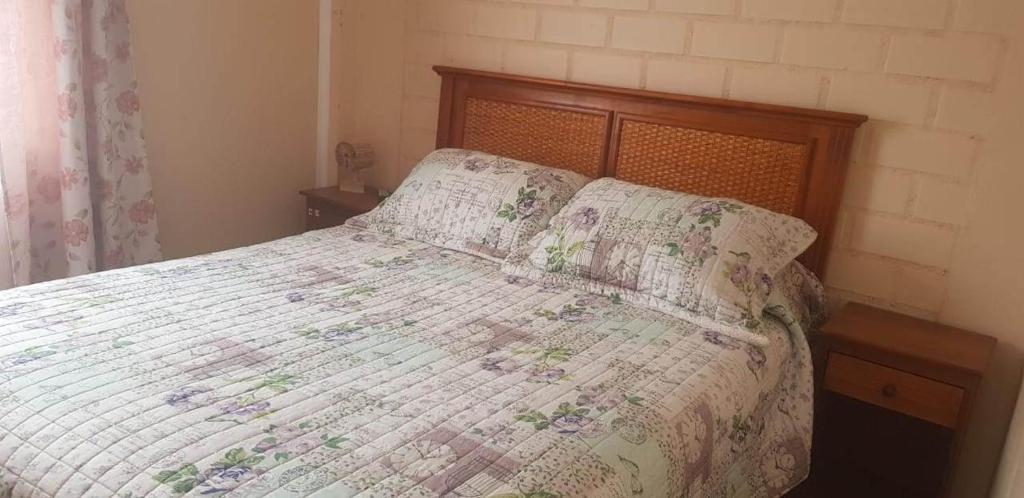 1 dormitorio con cama con edredón y almohadas en Casa Dichato, en Dichato