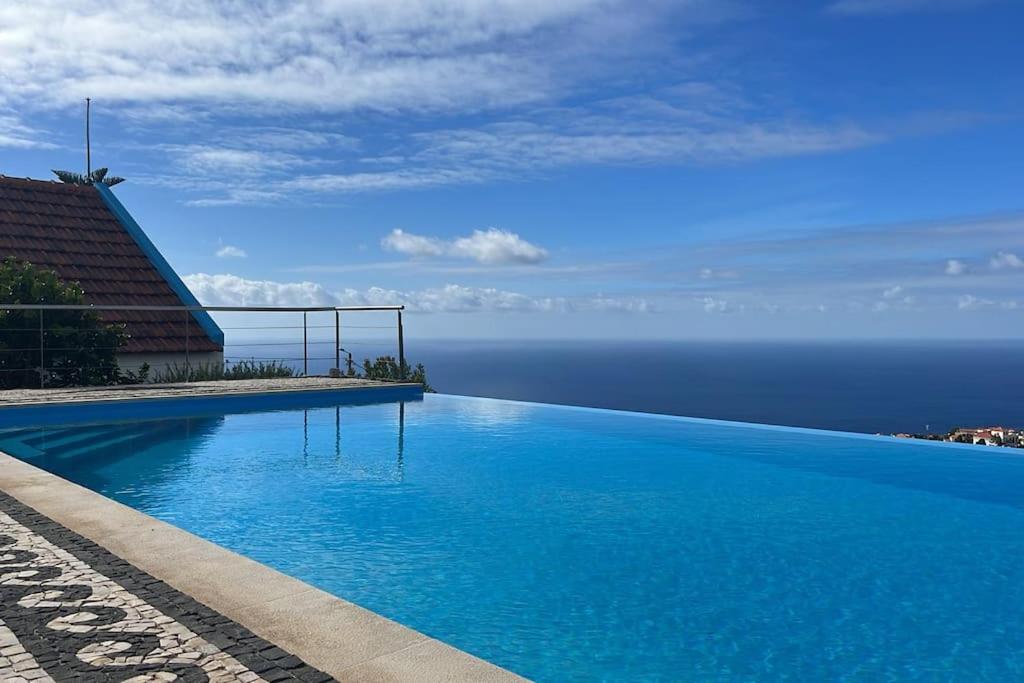 a blue swimming pool with the ocean in the background at Lucky Lemons Boutique Houses Madeira 1 in Calheta