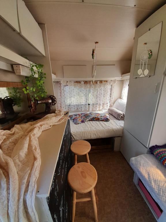 Cette petite chambre comprend un lit et un tabouret. dans l'établissement SA MOLA GLAMPING EXPERIENCE Roulotte, à Escolca