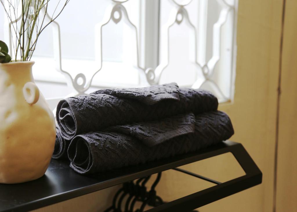 a pile of black towels on a black table with a vase at Vit-troi Room - Family 5 person - Duck Homestay Ben Tre in Ấp Phú Lợi