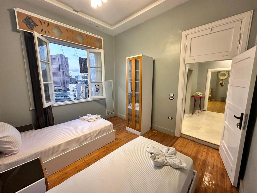 a bedroom with two beds and a large window at Midtown Nile View Suites in Cairo