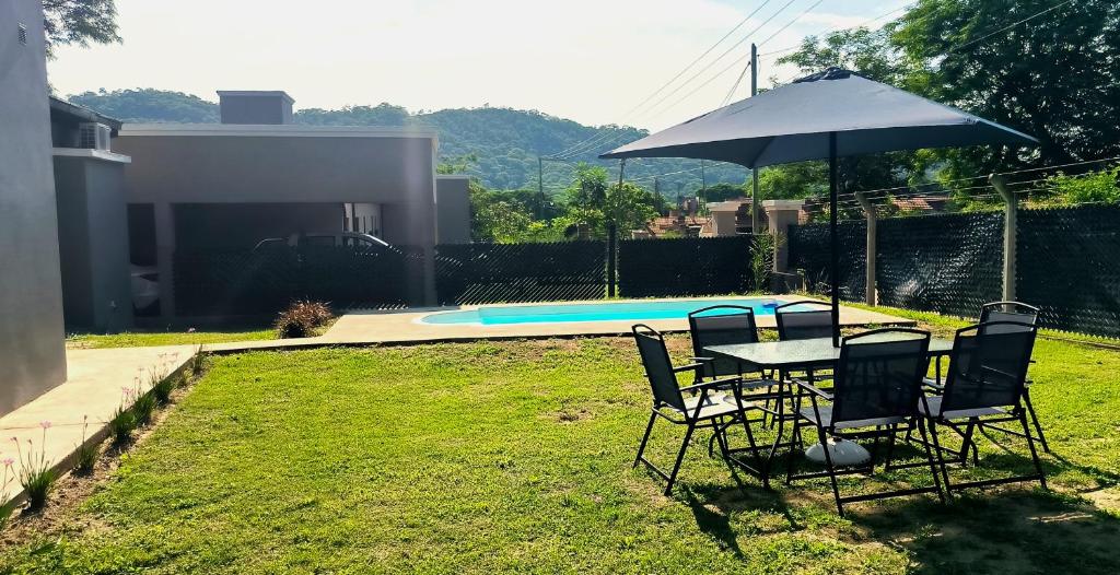 einen Tisch und Stühle mit einem Sonnenschirm neben einem Pool in der Unterkunft Casa de los Cerros - Vaqueros in Vaqueros