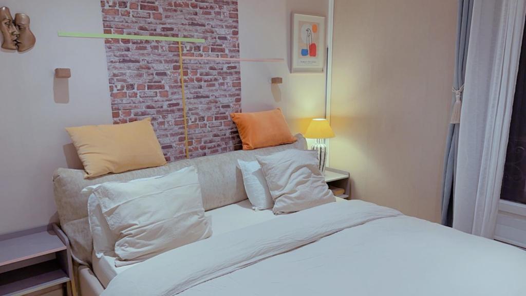 - une chambre avec un lit et un mur en briques dans l'établissement Cozy Paris Apartment, à Paris