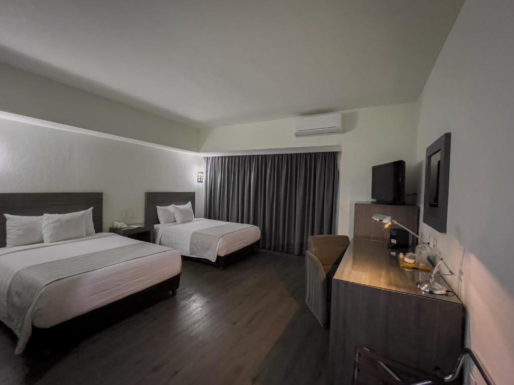 Cette chambre comprend deux lits et une télévision. dans l'établissement We Hotel Aeropuerto, à Mexico