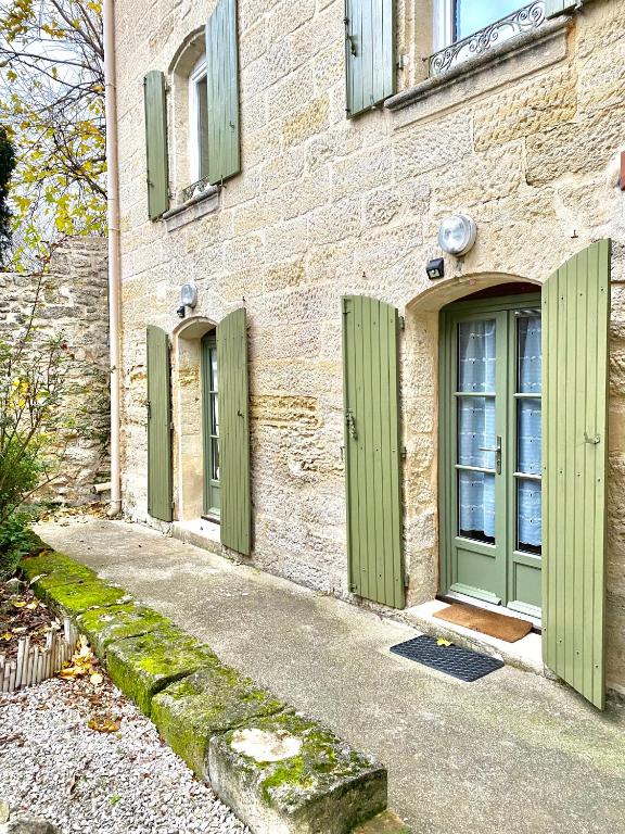 un bâtiment avec des portes vertes sur son côté dans l'établissement Grand studio sur jardin en centre-ville, à Uzès