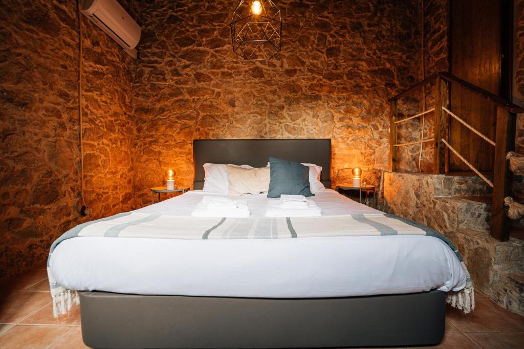 um quarto com uma cama grande numa parede de pedra em Casinhas Fim do Mundo em Reguengo Grande