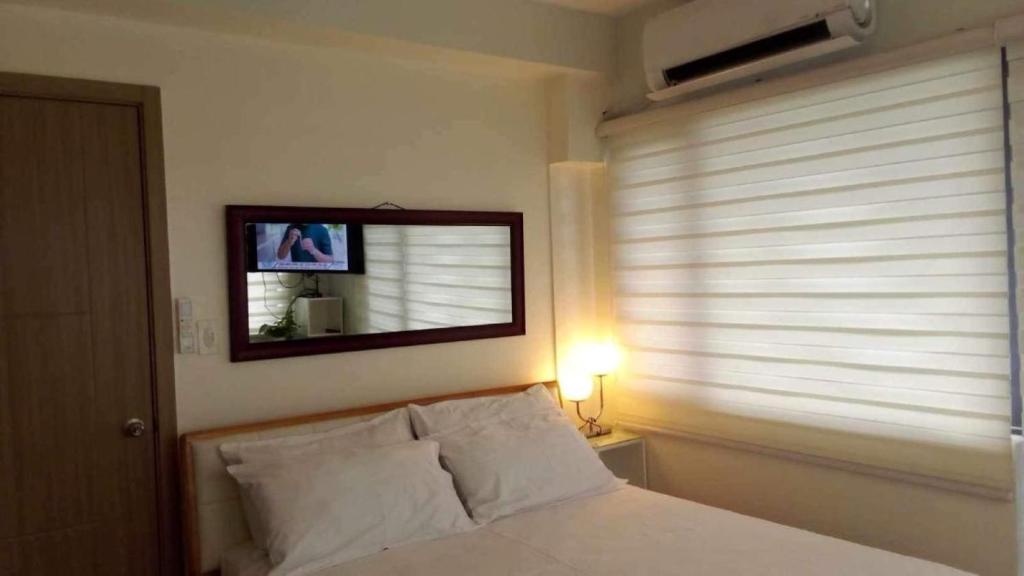 Schlafzimmer mit einem Bett mit einem Spiegel und einem Fenster in der Unterkunft The SPLENDOR comfortable living by Awsom Phil in Manila