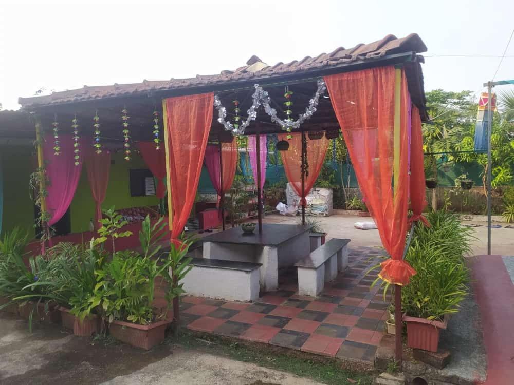 a gazebo with colorful curtains and plants at Kimaya farm house in Panvel