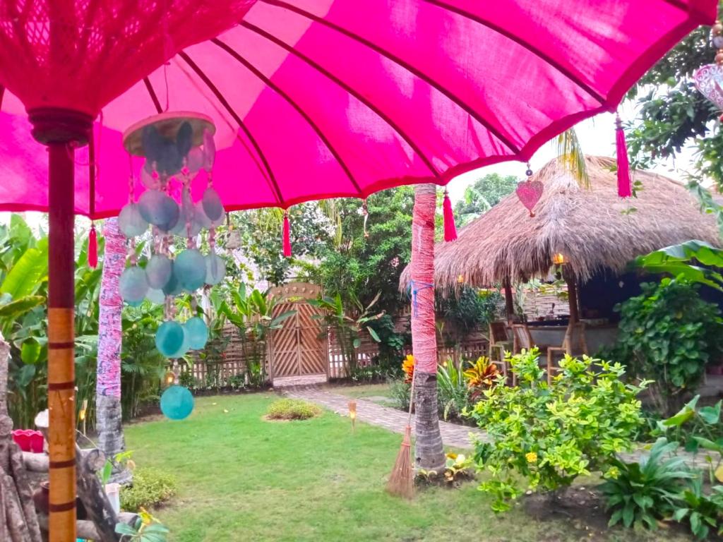 a group of pink umbrellas in a garden at UTOPIA BUNGALOWS in Gili Air