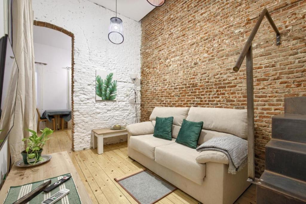 un soggiorno con divano e muro di mattoni di Charming Madrid Embajadores - Estancias Temporales a Madrid