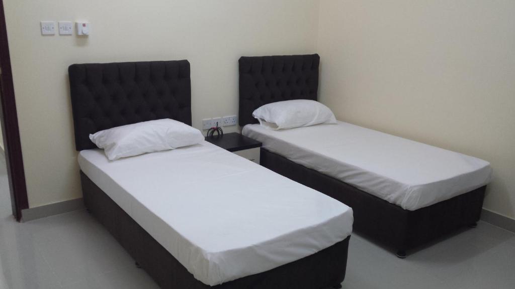 2 camas en una habitación con sábanas blancas en Golden Seasons Furnished Apartment, en Salalah