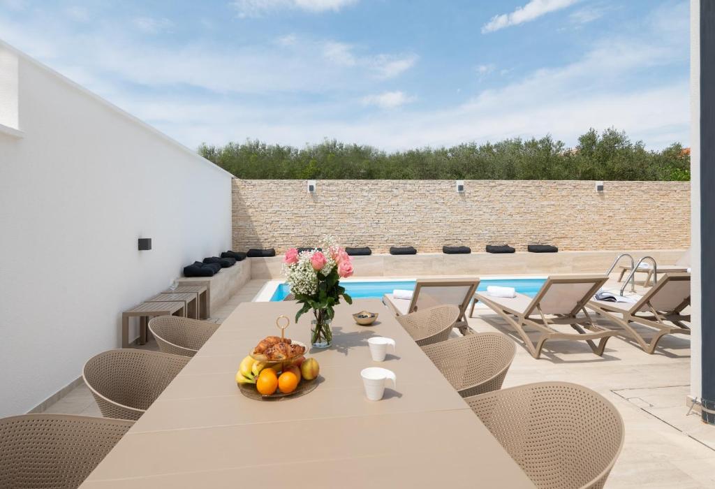 ein Esszimmer mit einem Tisch, Stühlen und einem Pool in der Unterkunft Villa Bellatrix 1 & 2 - two heated pools & jacuzzi in Vrsi